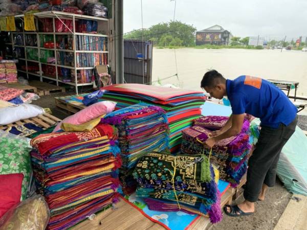 Salah seorang pekerja Naim mengemas karpet kecil yang perlu disimpan.