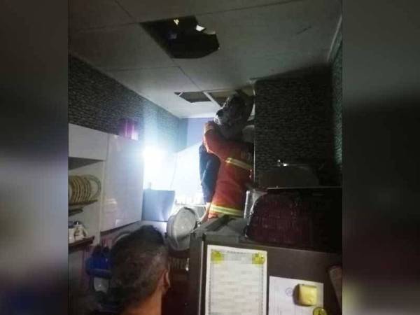 Anggota bomba mengeluarkan mangsa yang terperangkap dalam kebakaran rumah kedai di Taman Tampoi Indah malam tadi.