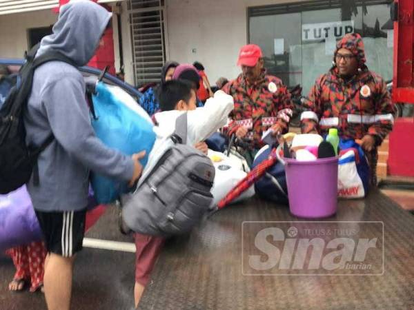 Anggota bomba bertungkus lumus memindahkan penduduk yang berada di kawasan ditenggelami banjir di sekitar Rantau Panjang.