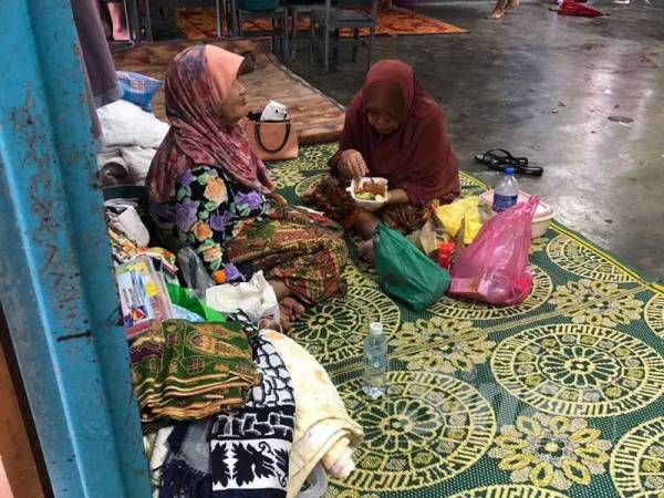 Penduduk yang ditempatkan di PPS di di jajahan Pasir Mas menikmati makanan.