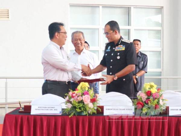 Ketua Setiausaha KDN, Datuk Jamil Rakon (kiri) menyerahkan dokumen penyerahan kompleks kepada Khairul Dzaimee (kanan) sebagai agensi peneraju kompleks ICQS sambil disaksikan Muhyiddin.