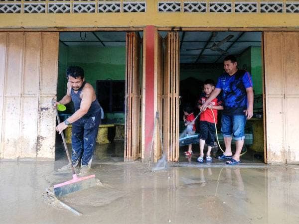 Mangsa banjir Raja Faisal Raja Sam'un, 43, (kiri) dibantu adik iparnya Ismail Mat Tahir, 45, membersih rumahnya yang dipenuhi lumpur ekoran banjir di Kampung La, Jerteh hari ini.
Lebih 300 mangsa melibatkan 66 keluarga di kampung tersebut terlibat dalam banjir yang berlaku sejak enam hari lalu. - fotoBERNAMA