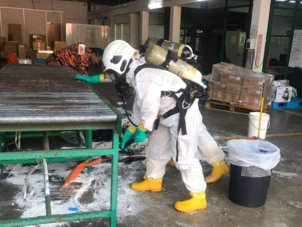 Anggota pasukan Hazmat melakukan operasi pembersihan kawasan tumpahan asid sulfurik di gudang sebuah syarikat kurier di Indera Mahkota di sini pagi tadi. -FOTO: IHSAN BOMBA