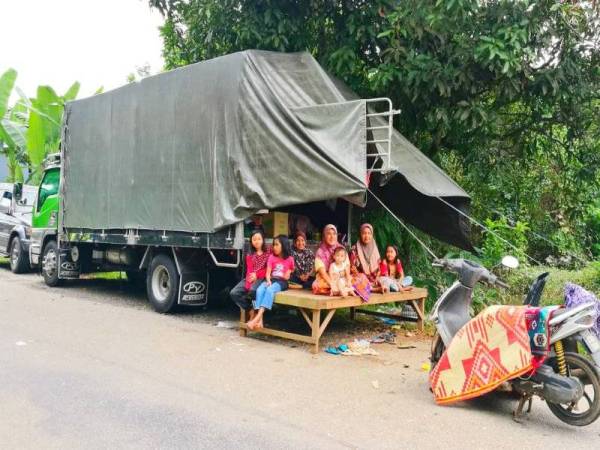 Marlina (empat dari kiri) bersama sebahagian ahli keluarganya terpaksa berhimpit di dalam lori seramai 17 orang apabila rumah mereka dinaiki air banjir.