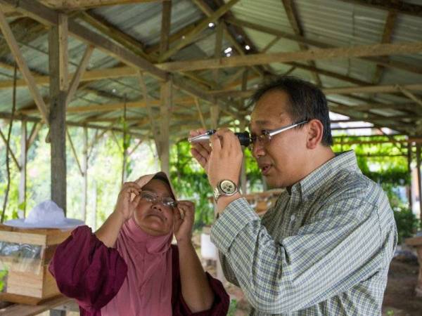 Shamsul Bahri (kanan) menunjukkan cara melihat kandungan gula dan kelembapan di dalam madu kepada Zainon. - Foto Prof Madya Dr Shamsul Bahri