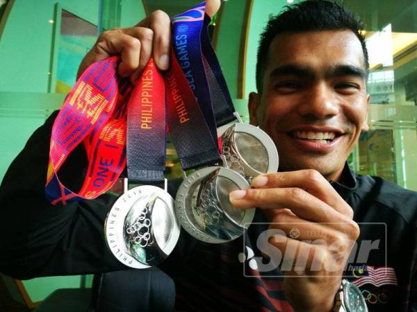 Mat Redho menunjukkan tiga pingat perak yang dimenanginya.