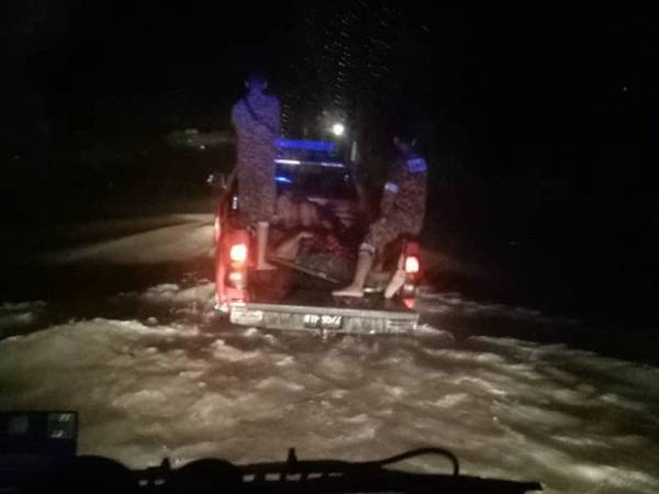 Anggota bomba meredah banjir untuk membantu membawa mayat mangsa ke Balai Polis Mawai malam tadi.