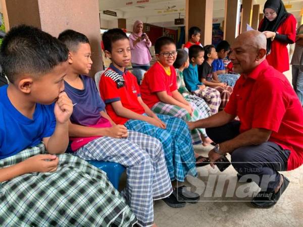 Anuar (kanan) berbual dengan peserta berkhatan di sini hari ini.