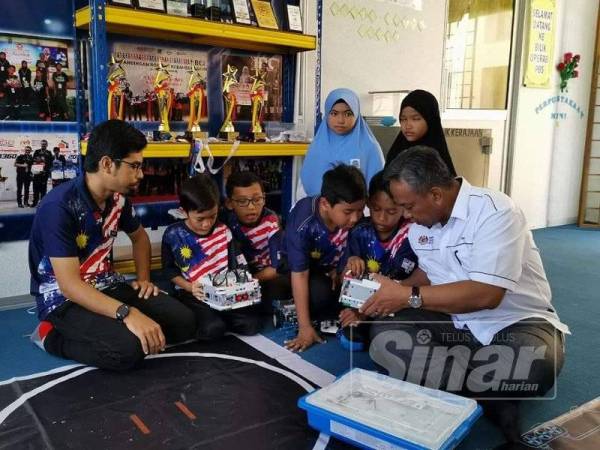 Mohd Razali (kanan) melihat ciptaan Mazlan dan murid SK Seri Terentang.