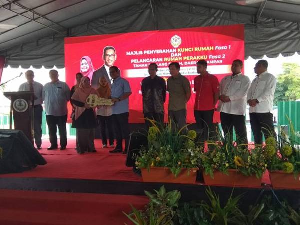 Ahmad Faizal menyampaikan replika kunci rumah kepada penerima pada Majlis Penyerahan Kunci Rumah Perakku Tualang Sekah di Tapak Projek Rumah Perakku di sini hari ini.