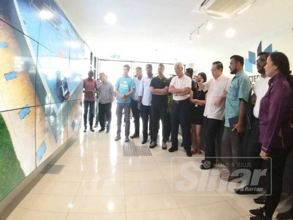 Guan Eng (tengah) sedang melihat video dari Perpustakaan Digital Butterworth dalam lawatannya hari ini.