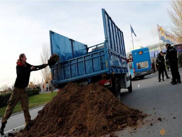 Aktivis membuang najis kuda di hadapan COP di Madrid semalam. - Foto: Agensi