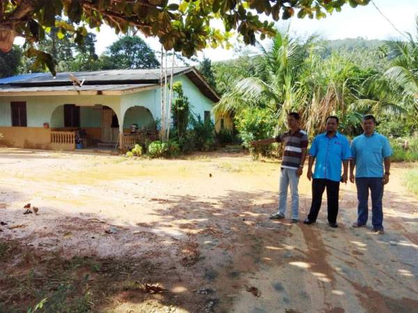 Mohd Aziz (kiri) menunjukkan kawasan rumahnya yang masih berlumpur tebal walaupun banjir sudah surut.