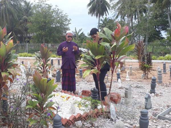 Zulkifli (kiri) ketika menziarahi pusara Muhammad Adib di Tanah Perkuburan Masjid Kampung Tebenggau.