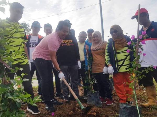 Mohd Shahar (dua dari kiri) menanam pokok bunga kertas di lokasi berhadapan UMP Gambang.