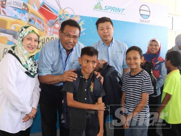 Sazally (dua dari kiri) menyampaikan sumbangan beg sekolah kepada salah seorang penerima bantuan Kembali Ke Sekolah pada majlis penyerahan di Kompleks Operasi Litrak di sini hari ini.