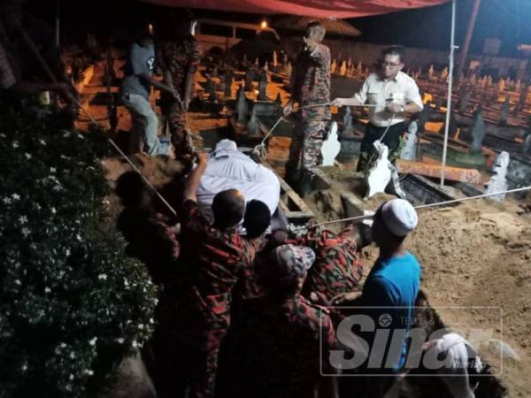 Orang kampung turut membantu anggota bomba untuk menurunkan jenazah ke liang lahad.