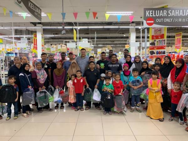 Tuan Peng (belakang, tengah) bergambar bersama penerima bantuan barangan kelengkapan sekolah di Pasaraya Econsave Permas Jaya di sini hari ini.