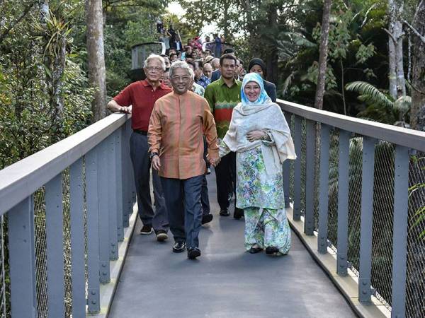 Yang di-Pertuan Agong, Al-Sultan Abdullah Ri'ayatuddin Al-Mustafa Billah Shah dan Raja Permaisuri Agong, Tunku Hajah Azizah Aminah Maimunah Iskandariah berpimpin tangan ketika berjalan di atas Canopy Walk sempena lawatan ke Bukit Bendera hari ini. - Foto Bernama