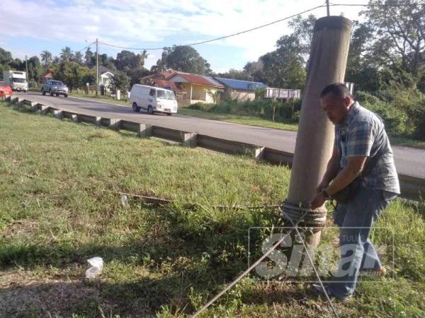 Khaidir memastikan tali yang diikat antara tiang dengan sangkarnya sentiasa kukuh bagi menghadapi musim tengkujuh.