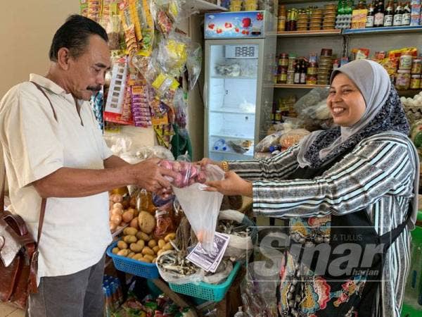 Azni (kiri) tetap membeli bawang merah untuk keperluan rumahnya.