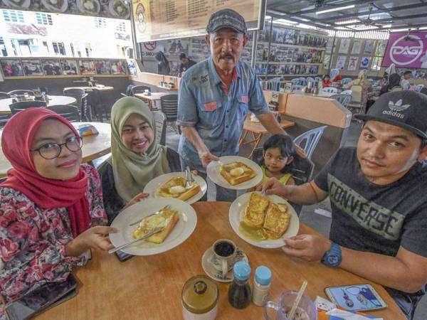 Nye Hua (kanan) menghantar sebahagian roti titab yang dipesan di kopitiam miliknya yang terletak di Taman Desa Jaya, Jalan Pengkalan Chepa. - Foto Bernama
