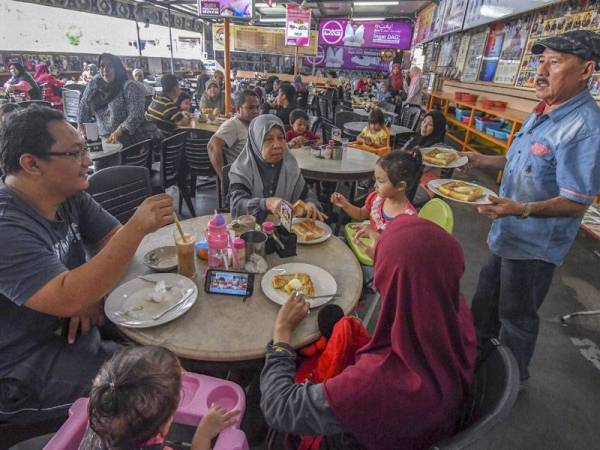 Nye Hua (tengah) melayan sebahagian pelanggan yang menikmati roti titab di kopitiam miliknya yang terletak di Taman Desa Jaya, Jalan Pengkalan Chepa.- Foto Bernama