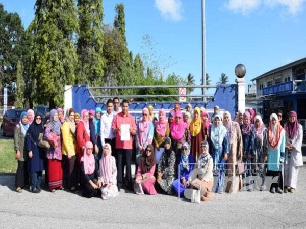 Alias memegang salinan laporan polis selepas membuat laporan polis bersama sebahagian kakitangannya di Balai Polis Chukai di sini.