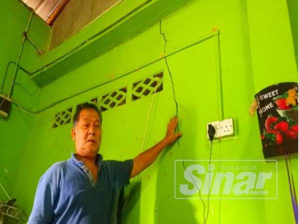 Ibrahim menunjukkan dinding rumah retak akibat hakisan.