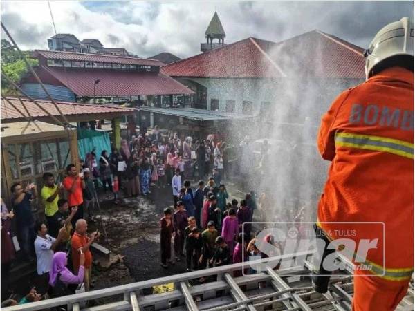 Suasana meriah di pekarangan surau apabila bomba menyiram peserta sebelum berkhatan.