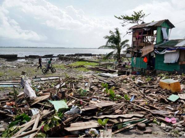 Penduduk berjalan melewati sebuah rumah yang rosak akibat Taufan Phanfone yang melanda Tacloban, wilayah Leyte pada Hari Krismas semalam. - Foto AFP