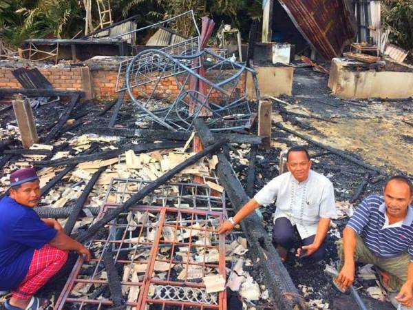 Samsudin (dua,kanan) dan Mohd Azmi (kanan) menunjukkan keadaan rumah Mohd Nor yang musnah akibat terbakar.