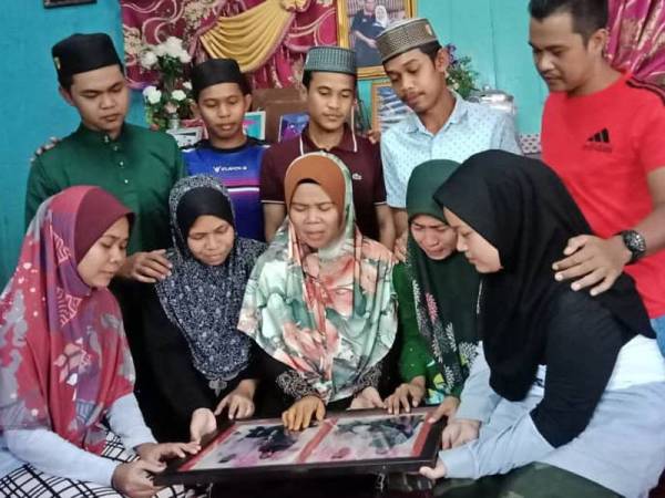Anak arwah menunjukkan gambar ibu bapa mereka yang menjadi kenangan untuk keluarga itu.
