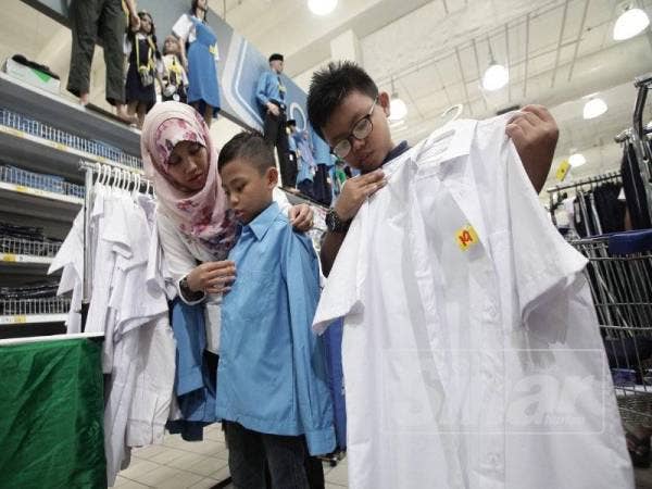 Khuzaimah dan anak-anaknya, Muhammad Sirhan Irsyad (tengah) serta Muhammad Sirhan Asif, 10, memilih baju sekolah di Mydin. - Foto Sinar Harian ZAHID IZZANI