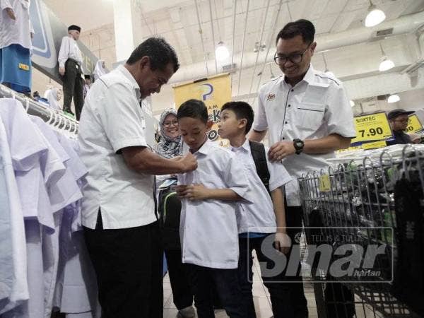 Mazlan (kiri) membantu penerima memilih baju sekolah sempena Program Back To School Anggota Ibu Pejabat LPP. - Foto Sinar Harian ZAHID IZZANI