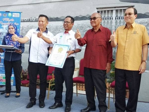 Borhan (tengah) menunjukkan sijil pengiktirafan yang diterima daripada pihak The Malaysia Book of Records menerusi lukisan mural 3D terbesar di luar bangunan di Malaysia.