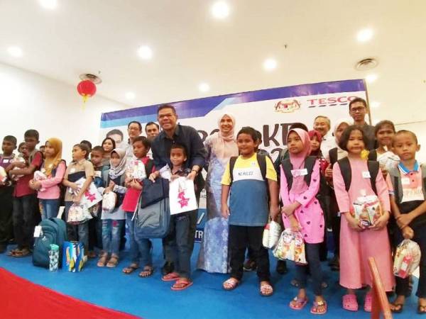 Saifuddin (tengah) bersama penerima pada program Kembali Ke Sekolah Bersama Tesco di Tesco Extra di sini hari ini.