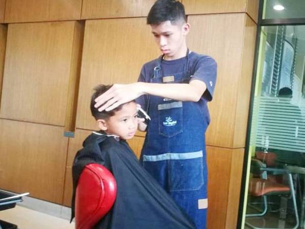 Seorang kanak-kanak sedang menggunting rambut.