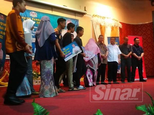 Saifuddin (empat dari kanan) selesai menyampaikan sumbangan RM100 kepada pelajar di SMKTPP hari ini.