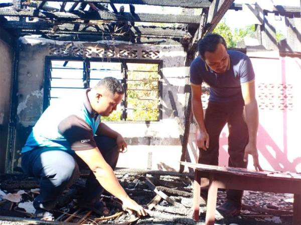 Sallehudin (kiri) dan Mohd Haffis melihat keadaan rumah pusaka keluarga mereka yang terbakar Jumaat lalu di Kampung Rambutan, Kuala Nerang.