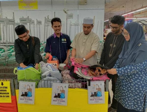 Amir (tengah) melihat barangan keperluan sekolah yang dikumpulkan di kaunter yang tertulis 'Preloved Back To School' di Pasaraya Econsave Bandar Puteri Jaya Sungai Petani.