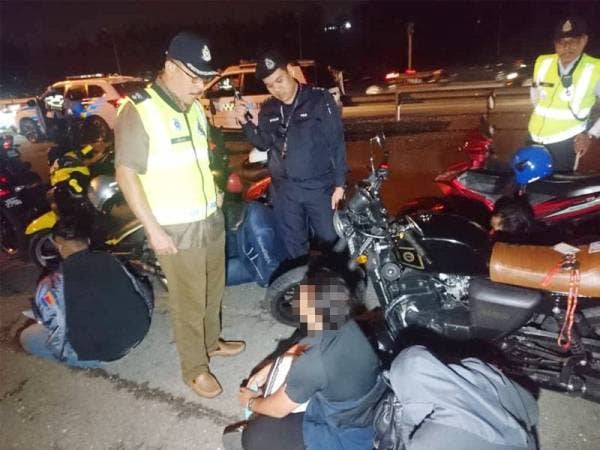 Azman (kiri) ketika pemeriksaan terhadap salah seorang penunggang motosikal.