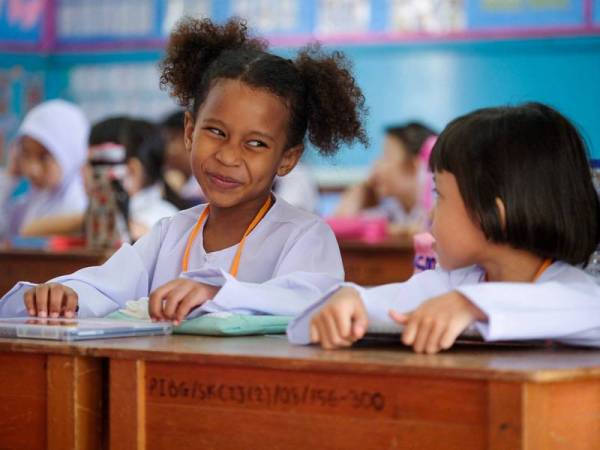 Seorang murid tahun satu Aleesa Amarachukwu Daniel (kiri) cuba menyesuaikan diri dengan rakan sekelasnya Siti Nurdanisha Adelia Muhamad Faizal (kanan) pada hari pertama sesi persekolahan 2020 yang bermula hari ini di Sekolah Kebangsaan Convent Infant Jesus dekat Bandar Hilir hari ini.- Foto Bernama