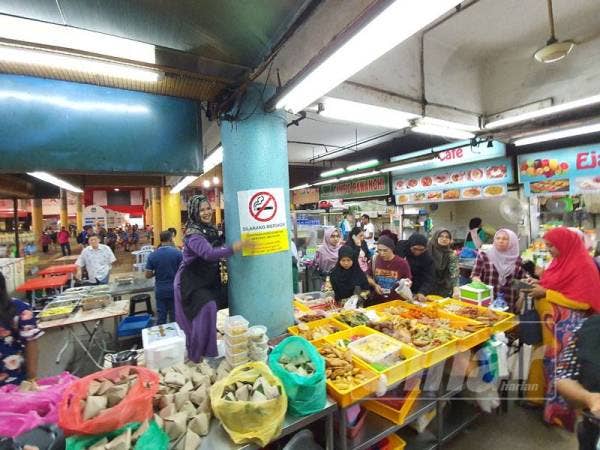 Seorang peniaga menampal notis larangan merokok di kedainya.