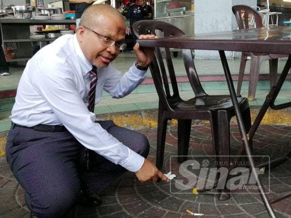 Dr Khalid menunjukkan notis larangan merokok yang mengikut spesifikasi (kiri) dengan yang lama (kanan).