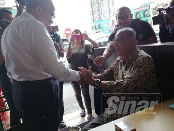 Dr Khalid (kiri) memberi peringatan kepada warga emas tersebut supaya tidak merokok dalam premis makanan atau berdepan kompaun sehingga RM350.