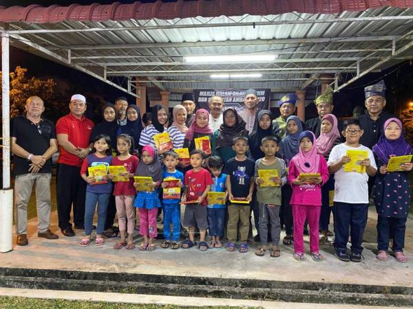 Abu Bakar bergambar bersama para pelajar miskin yang menerima sumbangan kelengkapan persekolahan sempena Program Kembali Ke Sekolah dan Bantuan Asnaf di Sungai Dua, baru-baru ini.