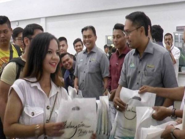 Asmirul (dua dari kanan) menyampaikan cenderahati kepada pelancong antarabangsa di ICQS baru-baru ini.