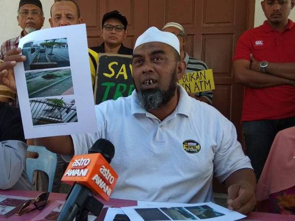 Shamsul Kamar menunjukkan gambar banjir lumpur yang pernah dialami penduduk Taman Chepor Sentosa akibat peneroka haram aktiviti pertanian berhampiran kawasan perumahan itu ketika sidang media hari ini.