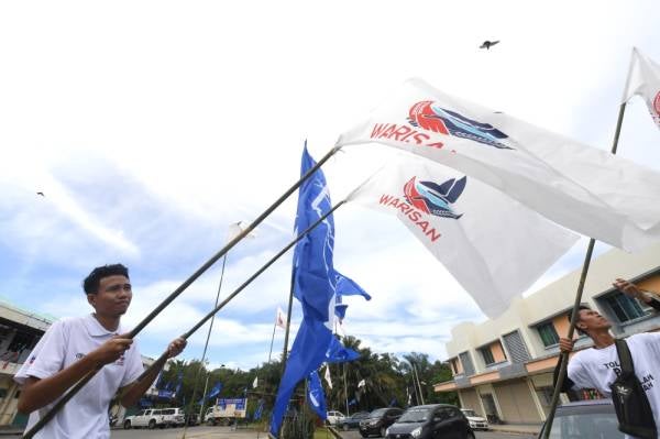 Seorang petugas membawa bendera parti Warisan untuk dipasang pada kempen sempena Pilihan Raya Kecil (PRK) Parlimen Kimanis, di Membakut. -Foto Bernama